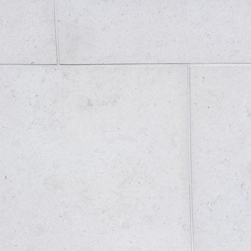 Dolce Ivory 18x18 limestone tiles with white texture, gray speckles, and precise grout lines