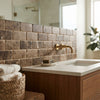 A sleek white rectangular basin with a brass faucet on a warm wood vanity and emperador dark marble 3x6 tumbled backsplash