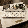 A herringbone-patterned mosaic tile panel of cream and dark brown spanish marble in emperador dark marble 4 3/4x12 basketweave border with crema marfil dots polished