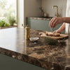 Brass pepper mill with ornate handle and cylindrical body paired with emperador dark marble 6x12 polished tile
