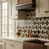 Dark brown copper range hood with black accents and curved fluted design in emperador dark marble lattice mosaic polished