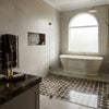 White marble freestanding bathtub with polished surface and subtle veining in emperador dark marble octagon mosaic design