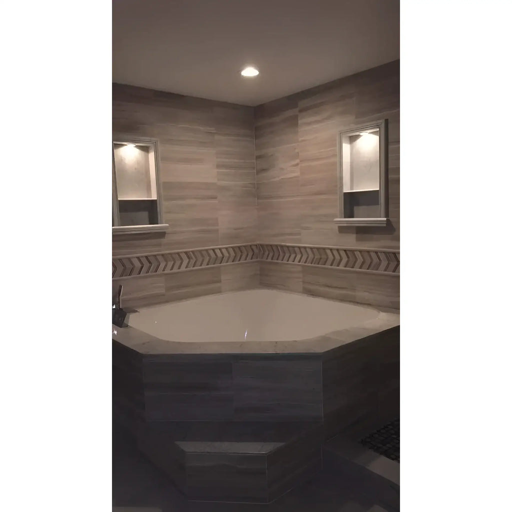 Corner bathtub with tiled surround featuring Hand Made Marble Shampoo Niche