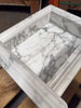 White marble shampoo niche with gray veining and fluted edge detail