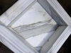 Handmade white marble shampoo niche with gray veining and ribbed border
