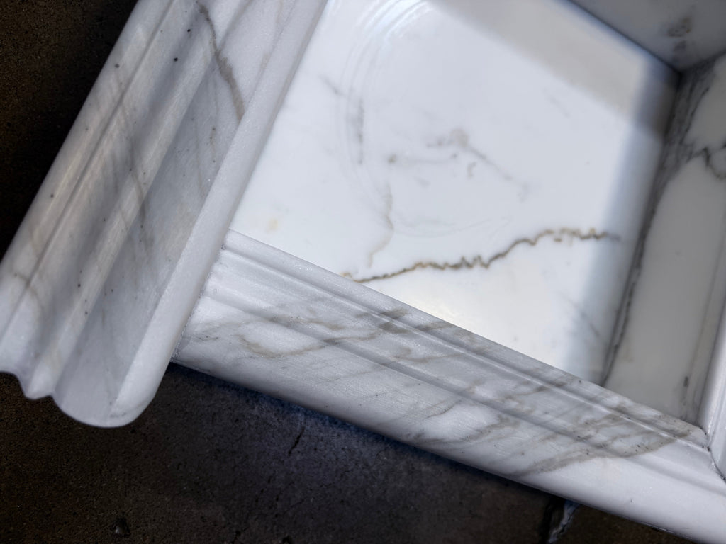 Handmade white marble shampoo niche with elegant veining and ornate rim
