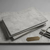 Stack of imperio grey 16x24 limestone antiqued tiles in light gray with textured surface and subtle veining