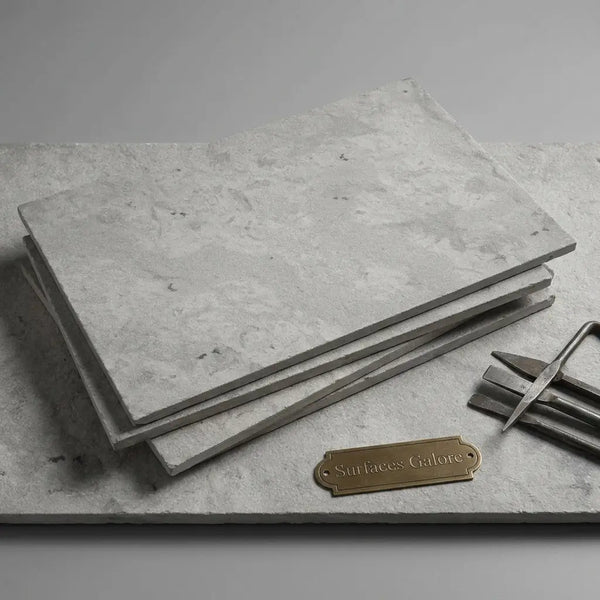 Stack of imperio grey 16x24 limestone antiqued tiles in light gray with textured surface and subtle veining