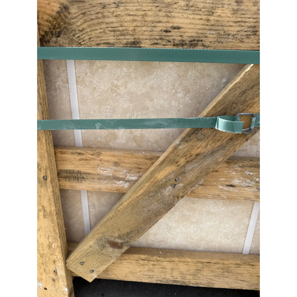 Wooden pallet with green straps holding Ivory Travertine 18X18 Cross-Cut stone tiles