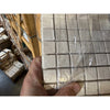 Hand holding Ivory Light Travertine 1x1 tumbled mosaic tiles