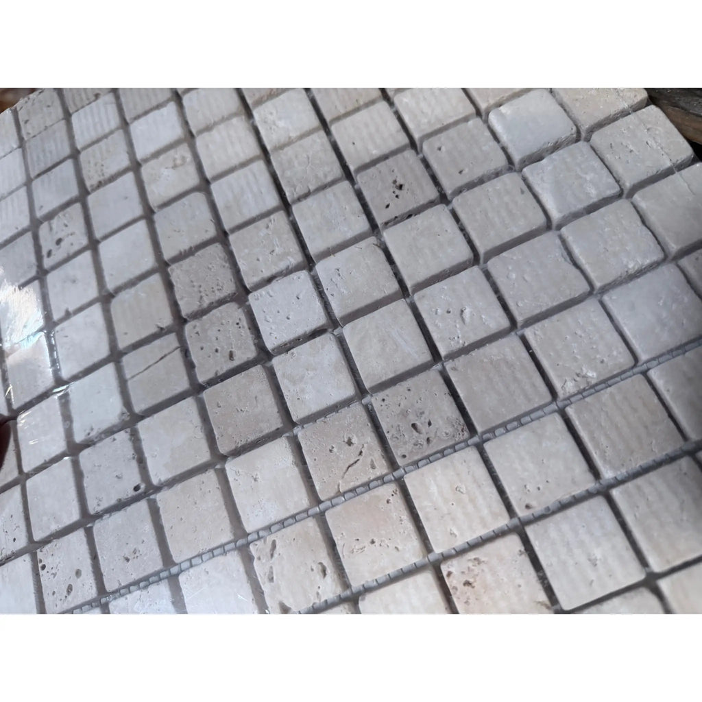 Ivory Light Travertine 1x1 tumbled mosaic tile in light gray with natural veining and matte texture