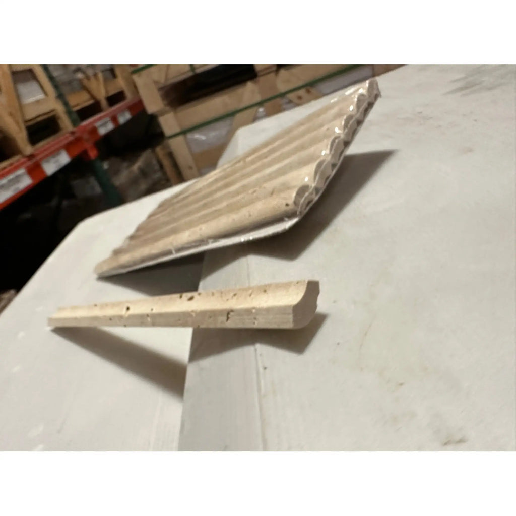 Light-colored textured travertine 1x6 quarter-round trim tile with rounded edge and speckled surface