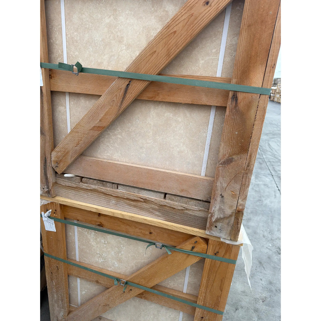 Rustic wooden crate with green straps securing Ivory Travertine 24x24 tiles