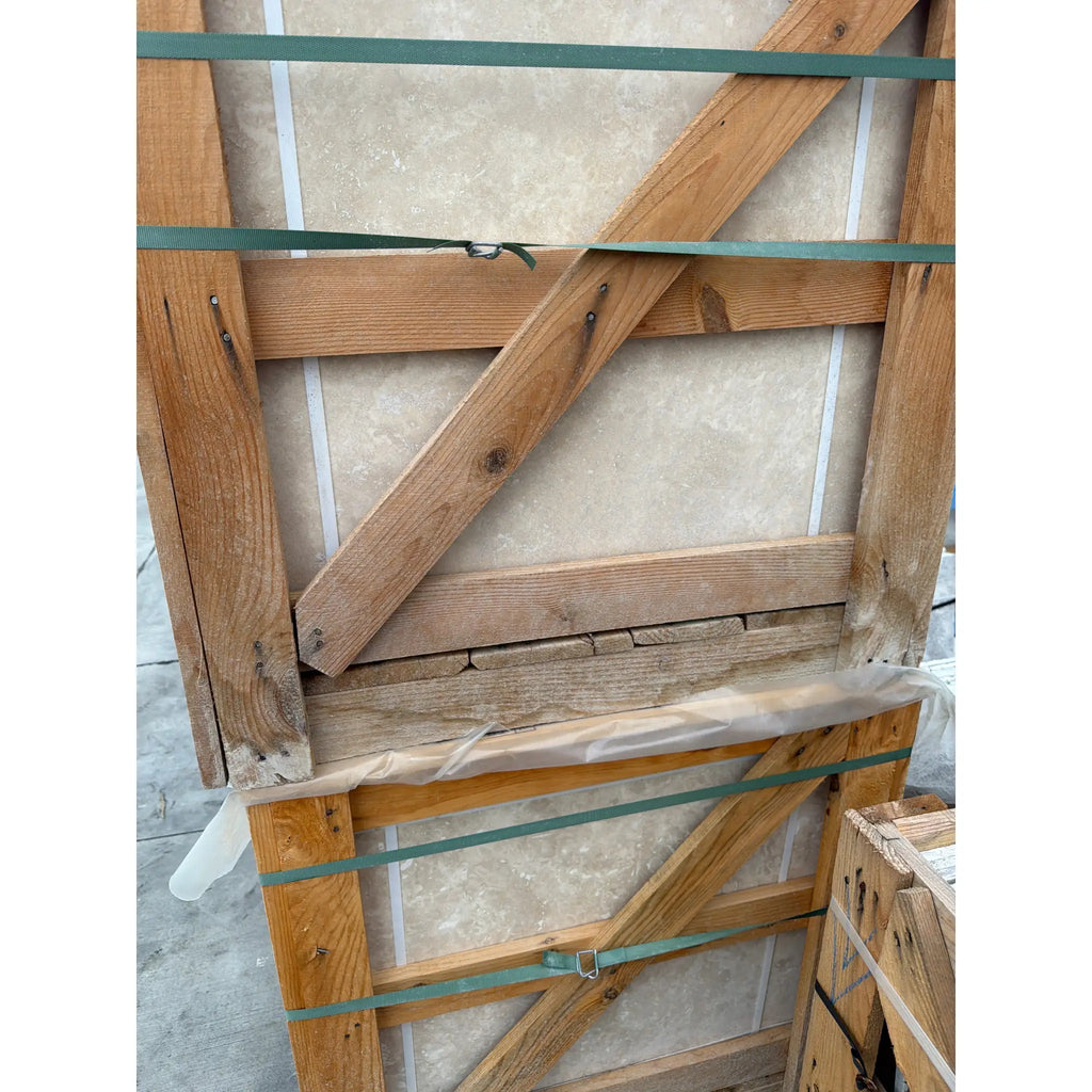 Rustic wooden crate with crossbeam, green straps holding Ivory Travertine 24x24 tiles