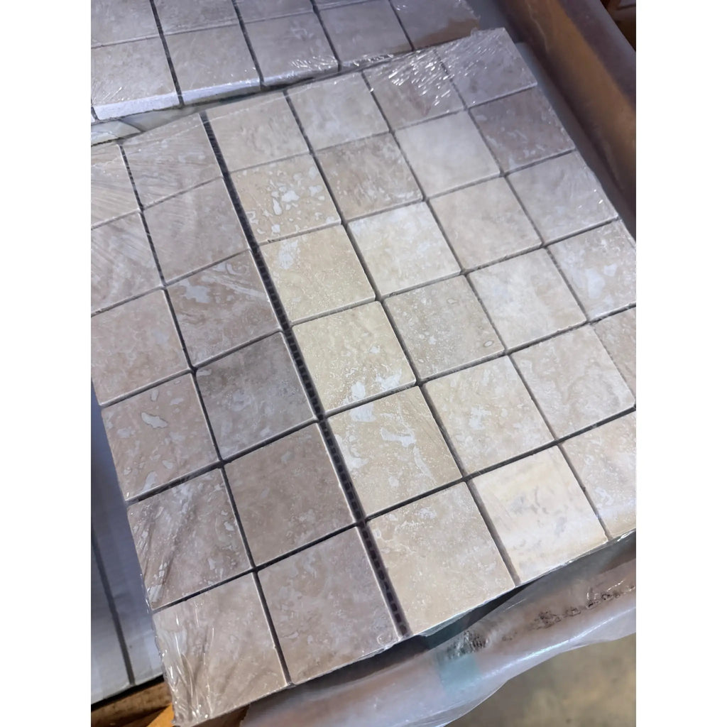 Ivory light travertine 2x2 mosaic filled and honed beige marble tiles with subtle veining wrapped in clear plastic