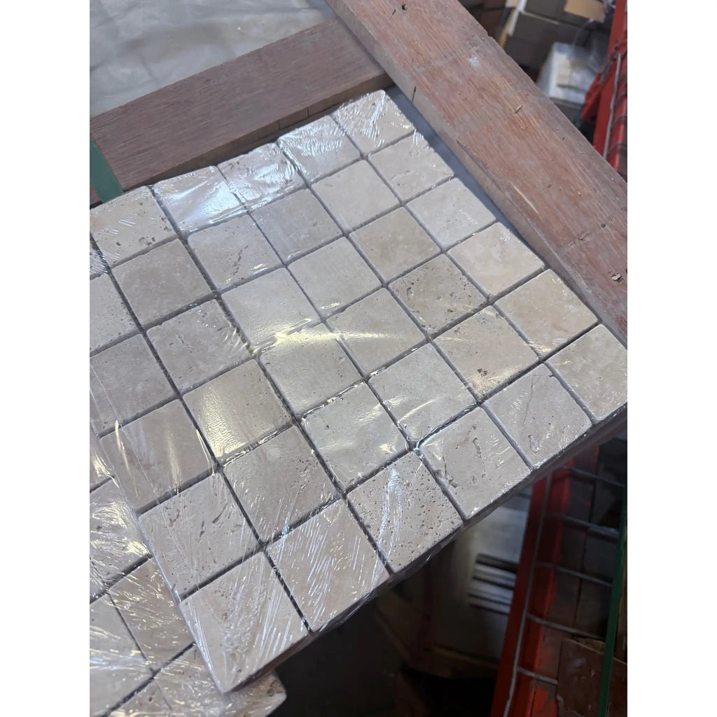Ivory light travertine 2x2 mosaic tumbled beige square tiles with natural stone texture wrapped in clear plastic