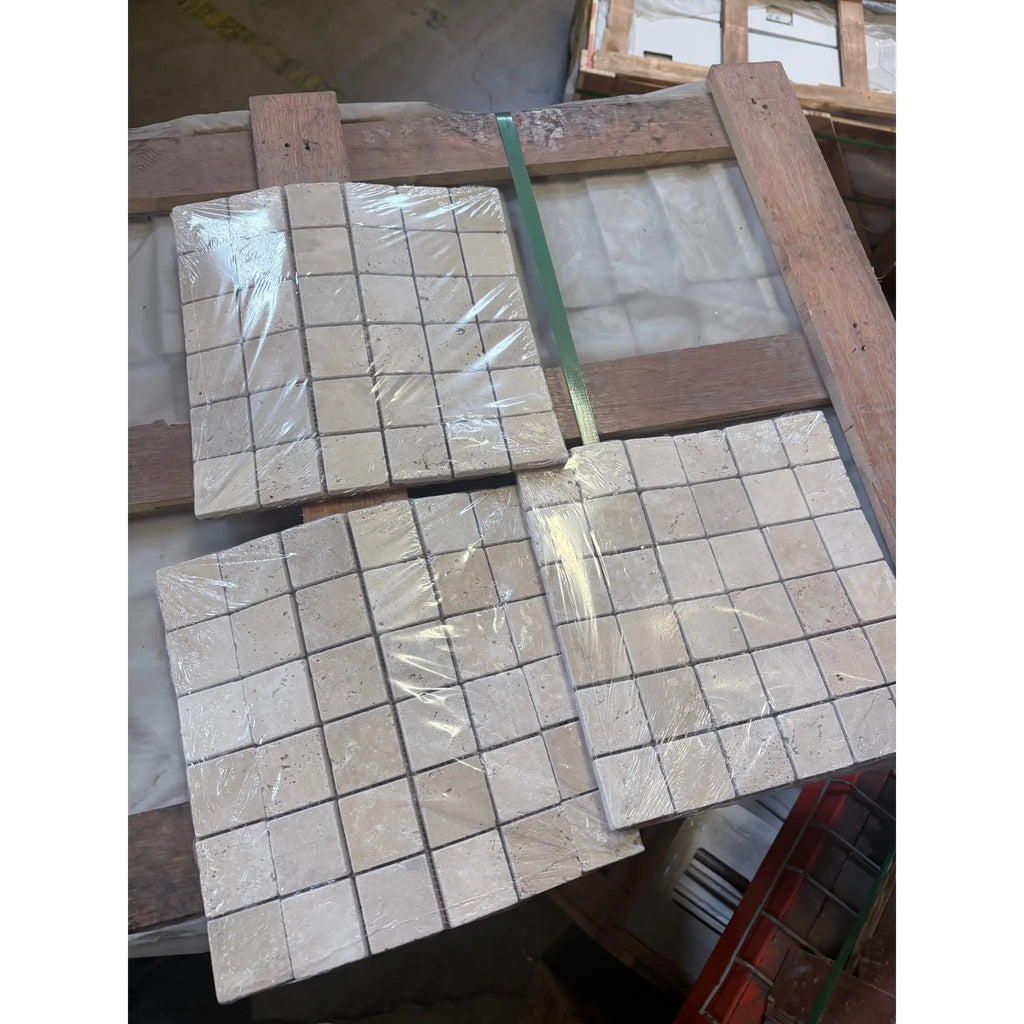 Beige ivory light travertine 2x2 mosaic tumbled stone tiles wrapped in clear plastic on wooden pallets