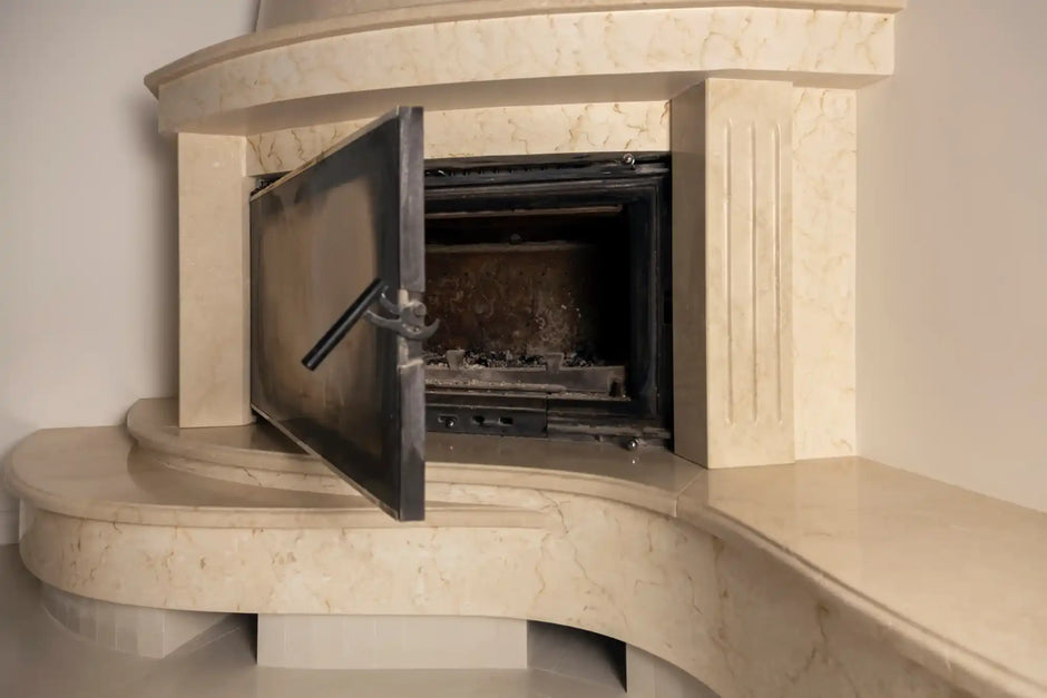 Marble fireplace with open metal door.