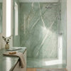 Modern showerhead with sleek chrome finish and circular design mounted on chrome arm in ming green jade green marble setting