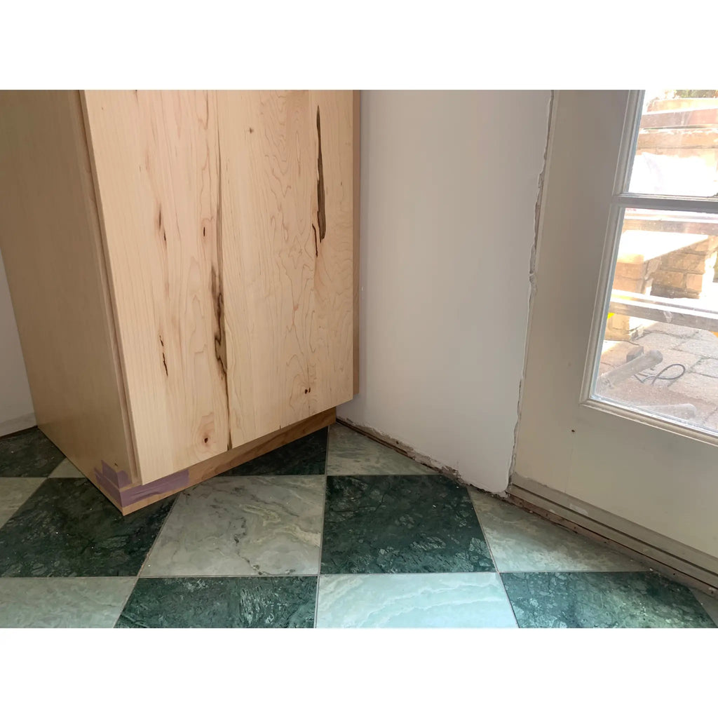 Light-colored wooden cabinet with visible grain and natural imperfections in ming green jade green 12x24 marble finish