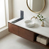 White marble vessel sink with gold-toned faucet on floating dark wood vanity with bianco dolomite and nero marquina tiles