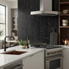 Stainless steel range with gold-colored knobs and sleek modern design paired with nero marquina black 1x4 herringbone marble mosaic