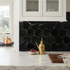 Gold oil dispenser with slender spout and polished metallic finish beside nero marquina black 3 inch hexagon marble mosaic tile