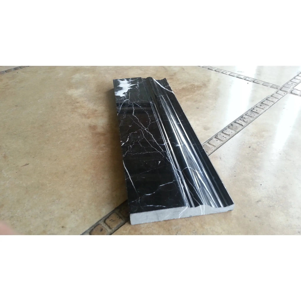 Nero marquina black marble baseboard trim with white veining and a sleek grooved polished or honed profile