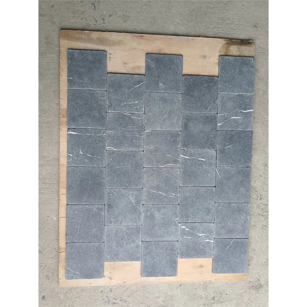 Dark gray rectangular nero marquina black marble 4x4 tumbled stone tiles with subtle white veining arranged in staggered pattern