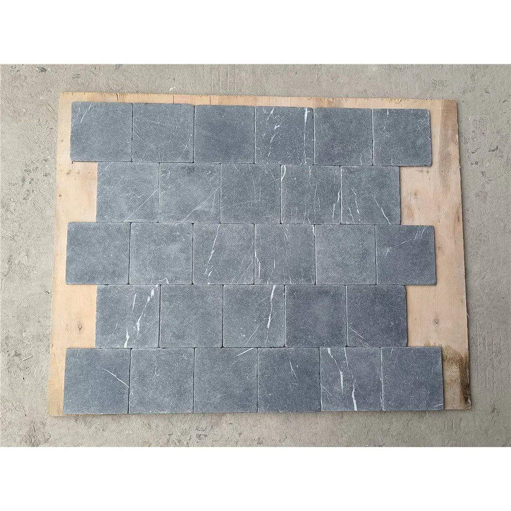 Dark gray nero marquina black marble 4x4 tumbled stone tiles with subtle white veining arranged in staggered pattern