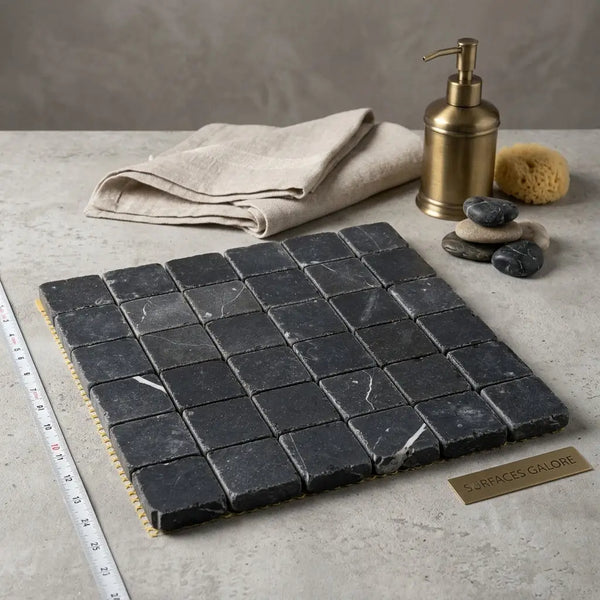 Dark gray Nero Marquina marble 2x2 tumbled mosaic tile panel with subtle white veining arranged in a grid pattern