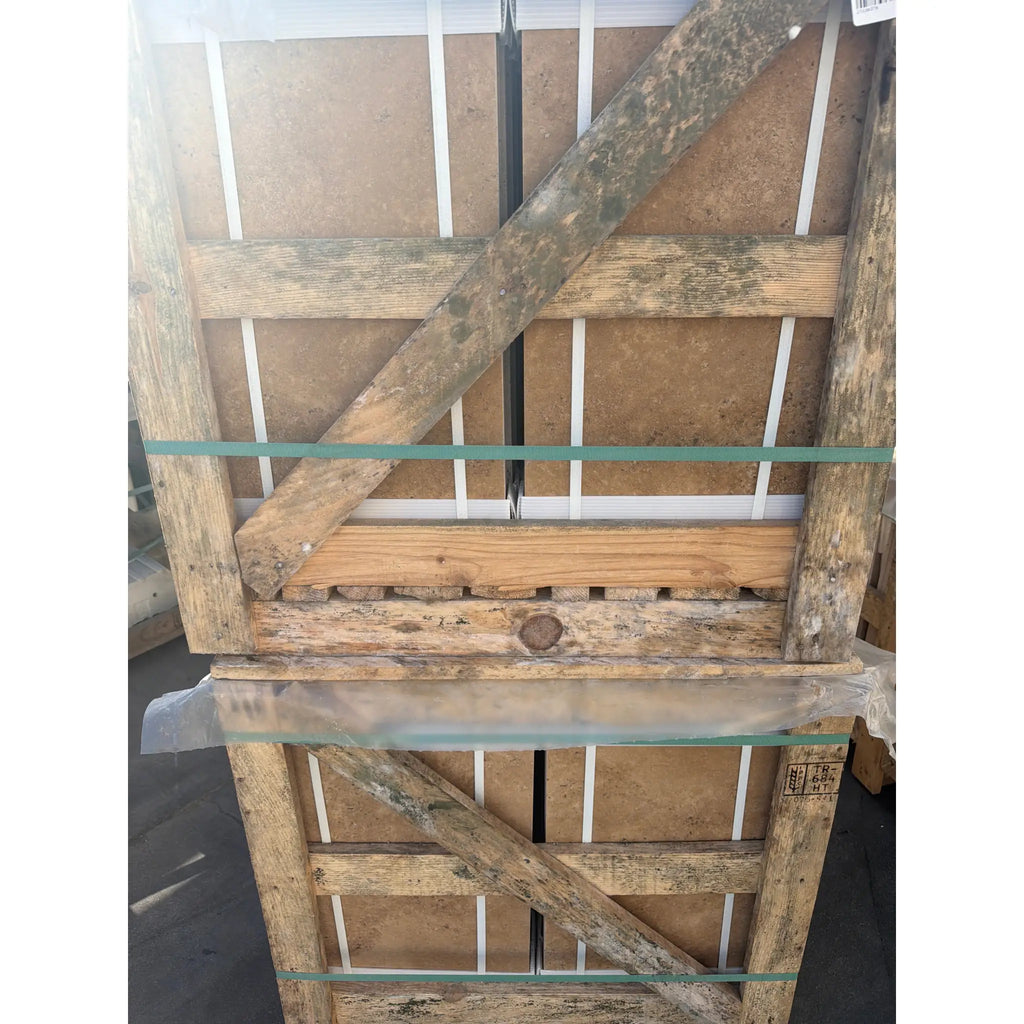 Weathered wooden pallet with visible grain and rustic texture secured by green plastic straps for noce brown travertine 12x24 cross-cut