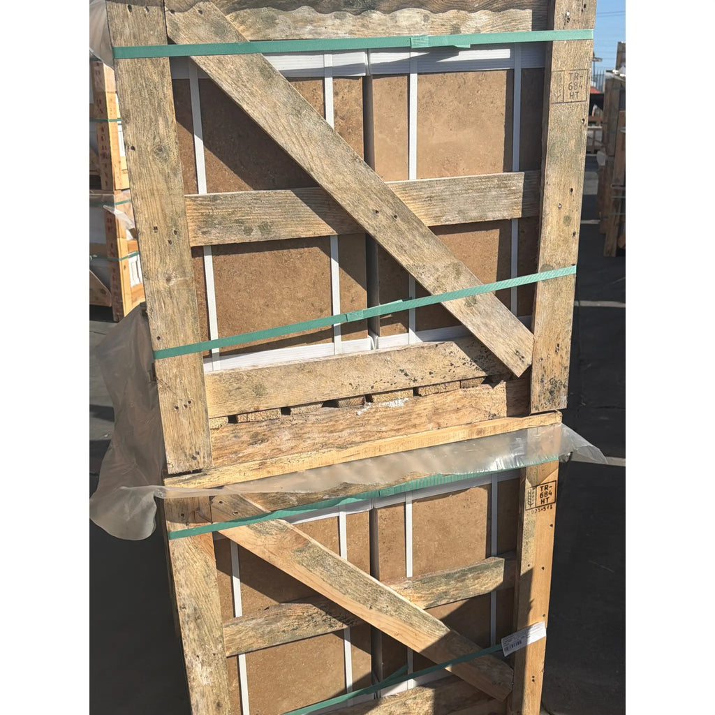 Weathered wooden pallet with green straps securing stacked noce brown travertine 12x24 cross-cut filled and honed panels