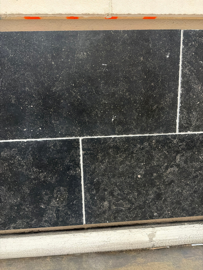 Obsidian Ash 16x24 honed limestone tiles in black textured stone with white grout