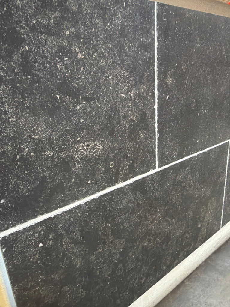 Obsidian Ash 16x24 honed limestone tiles in dark gray speckled texture with white grout