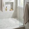 Beige waffle-weave towel hanging on chrome hook against oriental white asian statuary 2 inch hexagon marble mosaic tile