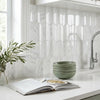 Stack of sage green ceramic bowls displayed with oriental white asian statuary 2x4 round-faced marble mosaic tile