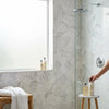 A sleek minimalist circular showerhead with polished chrome finish shown above an oriental white asian statuary hexagon marble mosaic