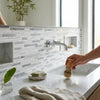 A wooden-handled shaving brush with natural bristles held near a polished oriental white asian statuary bamboo sticks marble sink