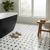 Black freestanding bathtub with sleek modern design shown with oriental white asian statuary basketweave marble mosaic