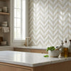 White marble countertop with gold-toned faucet and wooden cabinets featuring oriental white asian statuary chevron mosaic