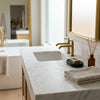 White marble bathroom countertop with integrated sink and gold-toned faucets in oriental white asian statuary marble 12x12 polished