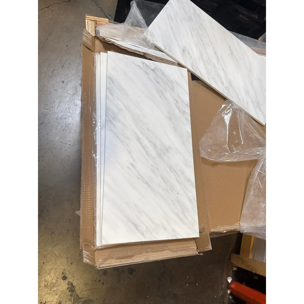 Stacked white marble-patterned tiles in a cardboard box for Oriental White Asian Statuary Marble