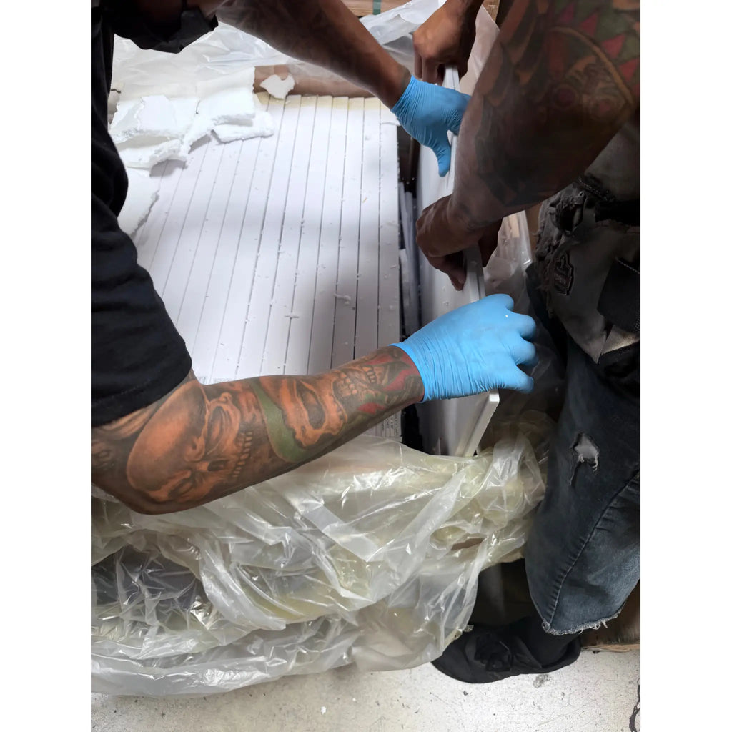 White rectangular oriental white asian statuary marble panels 18x36 polished wrapped in clear plastic handled with blue gloves