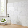 Clear glass soap dispenser with silver pump filled halfway with transparent liquid paired with oriental white asian statuary marble 4x12 polished