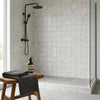 Black matte-finished showerhead with matching handheld spray and wall-mounted fixture on asian statuary marble tile