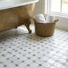 A woven wicker basket with white towels next to a brass clawfoot tub on oriental white asian statuary octagon mosaic with blue-gray marble mosaic polished floor
