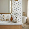 A rolled beige towel beside an amber soap dispenser and ceramic vase on oriental white asian statuary octave marble mosaic