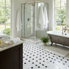 Antique-style clawfoot bathtub with metallic finish and ornate feet next to oriental white asian statuary pinwheel marble mosaic