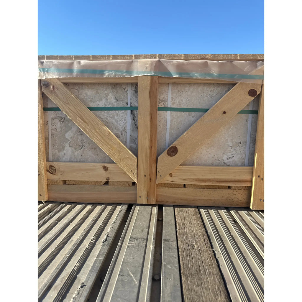 Wooden crate with light-colored Philadelphia Travertine 18x18 tiles secured with green straps
